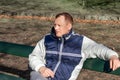 Portrait of a middle aged man sitting on a park bench