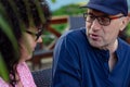 Portrait of middle-aged man sitting at table in cafe park outdoors, discussing having conversation with curly woman. Royalty Free Stock Photo