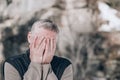 Portrait of a middle-aged man on the street, covering his face with his hands. Space for text Royalty Free Stock Photo