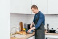 Portrait of middle-aged man in blue long-sleeve shirt, black apron beating eggs in blue plastic bowl with wire whisk Royalty Free Stock Photo