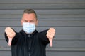 Portrait of a middle-aged man wearing protection mask while showing thumb down Royalty Free Stock Photo