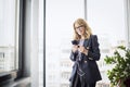 Portrait of middle aged smiling business woman using smartphone and earphones at the office Royalty Free Stock Photo