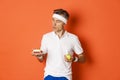 Portrait of middle-aged sportsman making decision between green apple and cake, being on diet, standing over orange