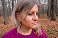 Portrait of middle aged woman in autumn forest. Girl does not look at camera on blurred background. Thought, meditation or doubt Royalty Free Stock Photo