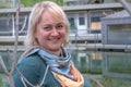 Portrait of a middle-aged woman with blond hair against the backdrop of a pond and a country house Royalty Free Stock Photo