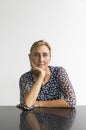 Portrait of a middle-aged woman with blond hair in a ponytail with a window with white wall behind her Royalty Free Stock Photo