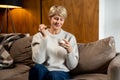 Portrait of a middle-aged woman who eats yogurt sitting on the couch at home Royalty Free Stock Photo