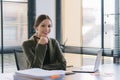A portrait of a millennial businesswoman in a stylish dress is sitting at desk in modern office, using a laptop computer Royalty Free Stock Photo