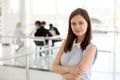 Portrait of millennial female employee posing with arms crossed