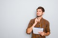 Portrait of minded man with notebook on gray background