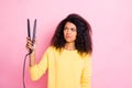 Portrait of minded pensive afro american girl hold look hair straightener think will it be good feel unsure wear yellow