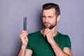 Portrait of minded pensive guy look comb feel unaware about haircare procedure wear green t-shirt isolated over gray