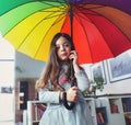 Portrait of a miserable little girl holding a colorful umbrella inside the house