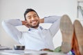 Portrait of a mixed race business man relaxing with his feet up at his desk. Boss looking relaxed and satisfied at Royalty Free Stock Photo