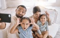 Portrait of a mixed race family taking a selfie and making funny faces while sitting on the sofa at home. Hispanic man Royalty Free Stock Photo
