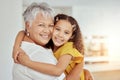 Portrait of mixed race grandmother and granddaughter hugging in living room at home. Smiling hispanic girl embracing Royalty Free Stock Photo