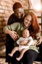 Portrait of mixed race smiling family sit on the stairs. Beautiful mother and smiling father holding baby boy. Joyful Royalty Free Stock Photo