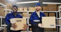 Portrait of mixed-races young male postmen in uniforms and caps holding carton boxes in hands.