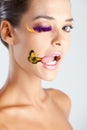 A model with false eyelashes a colourful butterfly near lips tongue out