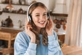 Portrait of modern blond girl 20s wearing headphones listening to music at home Royalty Free Stock Photo