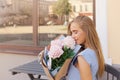 Portrait of modern fashion trendy women sitting in outdoor restaurant with Bouquet of peonies