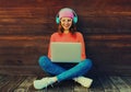 Portrait of modern happy smiling young woman working on laptop listening to music in headphones in the city park Royalty Free Stock Photo