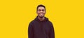 Portrait of modern smiling young african man looking at camera wearing black hoodie isolated on yellow background Royalty Free Stock Photo