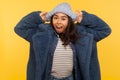 Portrait of modern surprised trendy girl in fur coat adjusting winter hat and looking at camera with amazement Royalty Free Stock Photo