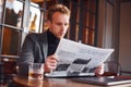 Portrait of modern young guy in formal clothes that sits in the cafe and reads newspaper Royalty Free Stock Photo