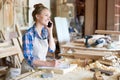 Young Woman Speaking By Smartphone in Modern Joinery Royalty Free Stock Photo