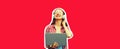 Portrait of modern young woman working with laptop listening to music in headphones on red background Royalty Free Stock Photo