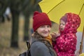 Portrait of mom and baby on the hands under yellow umbrella in park. Mother smiles and looking at camera. Autumn walking Royalty Free Stock Photo