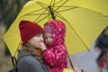 Portrait of mom and baby under a yellow umbrella in the autumn park. Baby looking at the camera Royalty Free Stock Photo