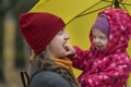 Portrait of mom and baby under yellow umbrella in park. Mom and little daughter fooling around