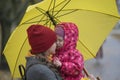 Portrait of mom who hugs her little daughter holding her in her arms under yellow umbrella in a yellow autumn park Royalty Free Stock Photo