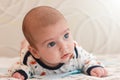 portrait of 2 months old adorable baby boy with big blue eyes and long eyelashes. cute baby lying on his stomach and looks away Royalty Free Stock Photo