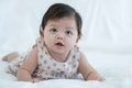Portrait of 3 months old newborn baby in white bed. Innocent adorable mixed race baby, Asian and Caucasian, is lying or crawling. Royalty Free Stock Photo