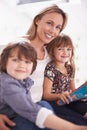 Portrait, mother and children on sofa reading book with bonding, teaching and learning together in home. Mom, son and Royalty Free Stock Photo