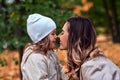 Portrait of mother and daughter, looking at each other and laughing touching noses. A walk in the autumn park. Motherhood, love Royalty Free Stock Photo