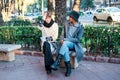 Portrait of a mother and daughter together embracing and sitting on a bench in the city