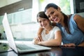 Portrait of mother and daughter using laptop and digital tablet in the living room Royalty Free Stock Photo