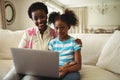 Portrait of mother and daughter using laptop in living room Royalty Free Stock Photo