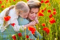 Portrait of mother and daughter walking through a flowering poppy field. Summer family holidays on nature. Summer on Royalty Free Stock Photo