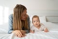 Portrait of a mother with a four month old baby in the bedroom. Young happy mum lies next to her adorable baby son, a Royalty Free Stock Photo