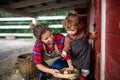 Portrait of mother with small daughter standing on farm, holding basket with eggs.