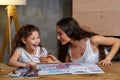 Portrait of a mother helping her small sweet and cute daughter to make her homework indoors. Happy family. Royalty Free Stock Photo