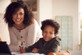 Portrait Of Mother Helping Son With Homework Sitting At Kitchen Counter Using Digital Tablet Royalty Free Stock Photo