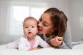 Portrait of a mother and her baby playing on the bed. The concept of happy parenthood