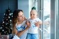 Portrait of mother hugging smiling son at home on Christmas eve. Happy young mother with baby against Christmas lights. Happy Royalty Free Stock Photo