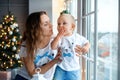 Portrait of mother hugging smiling son at home on Christmas eve. Happy young mother with baby against Christmas lights. Happy Royalty Free Stock Photo